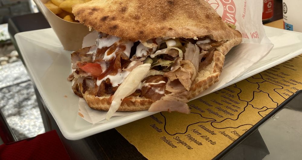 Kebab in piadina con salsa bianca e insalata, accompagnato da patatine fritte.