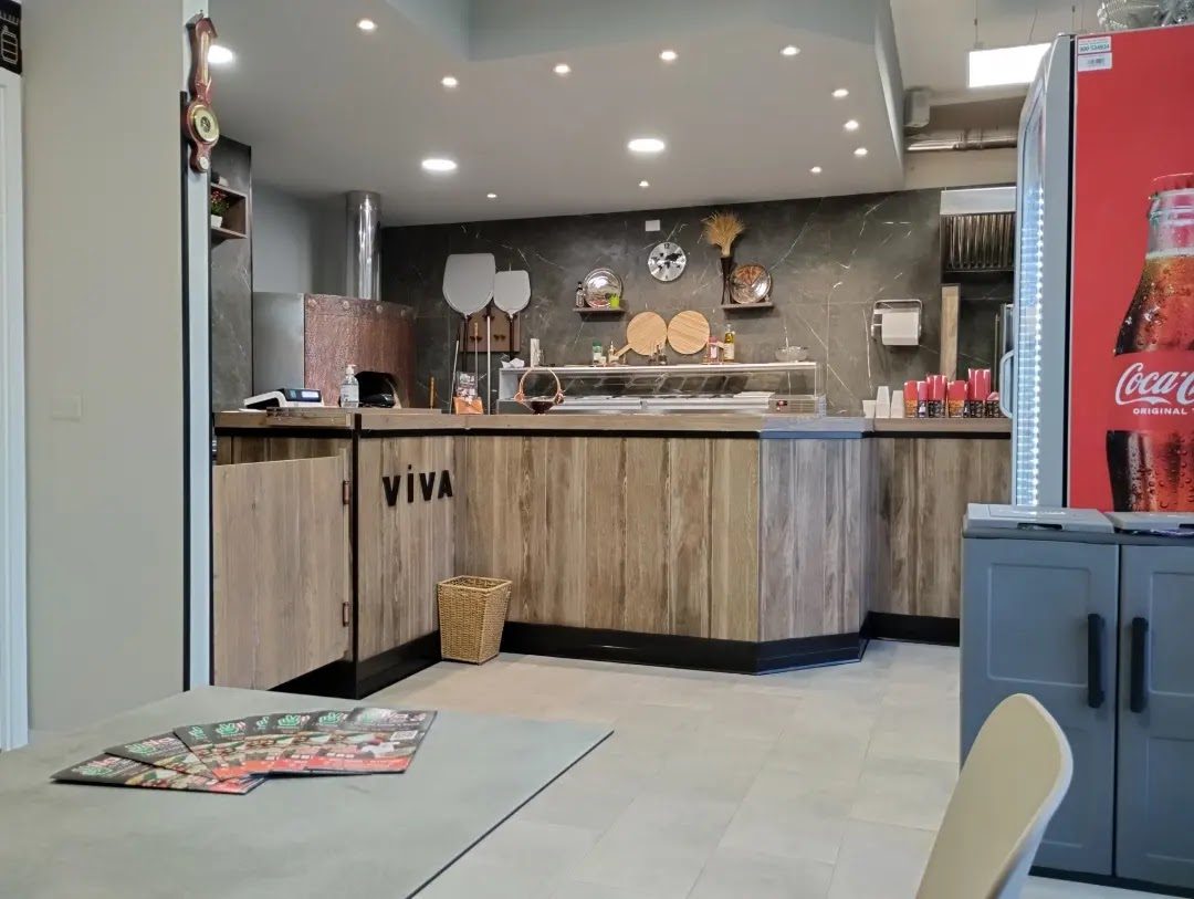 L'interno del locale: il bancone di legno con la scritta VIVA sul frontale e il banco frigo accanto.